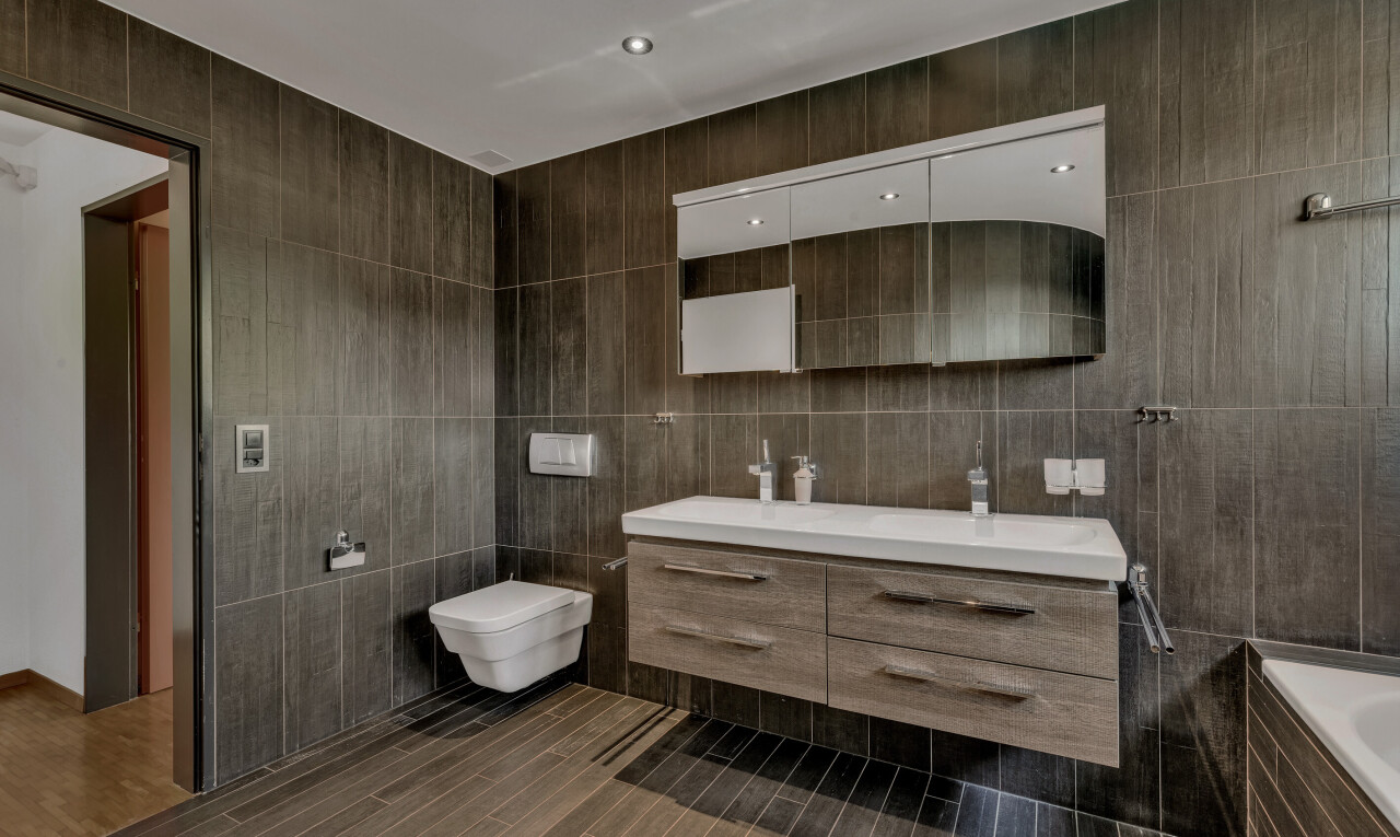 full bathroom with vanity, a relaxing tiled tub, tile walls, and dark wood-style flooring