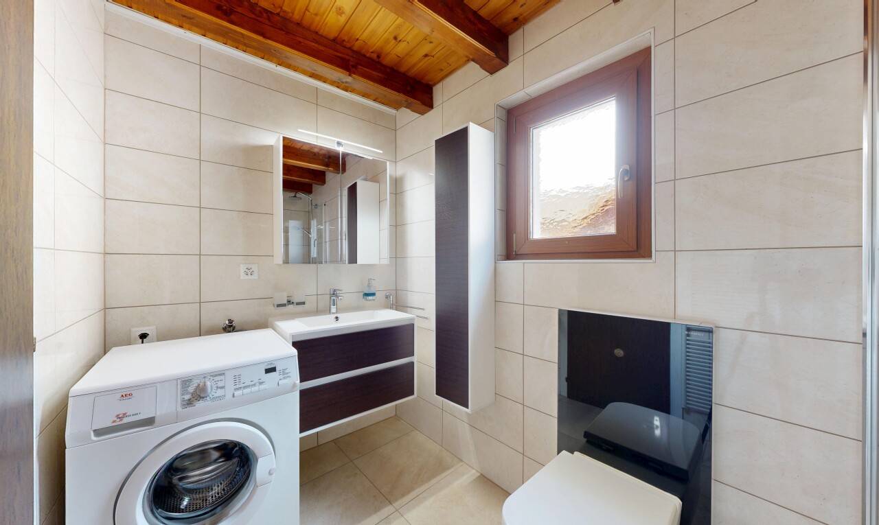salle de bains avec mur en carrelage, tile wall, lave-linge et sèche-linge, plafond à poutres, et beamed ceiling