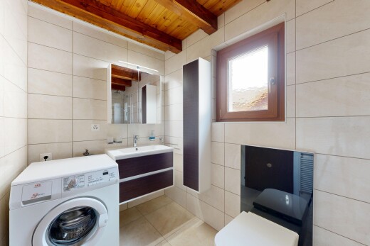 salle de bains avec mur en carrelage, tile wall, lave-linge et sèche-linge, plafond à poutres, et beamed ceiling