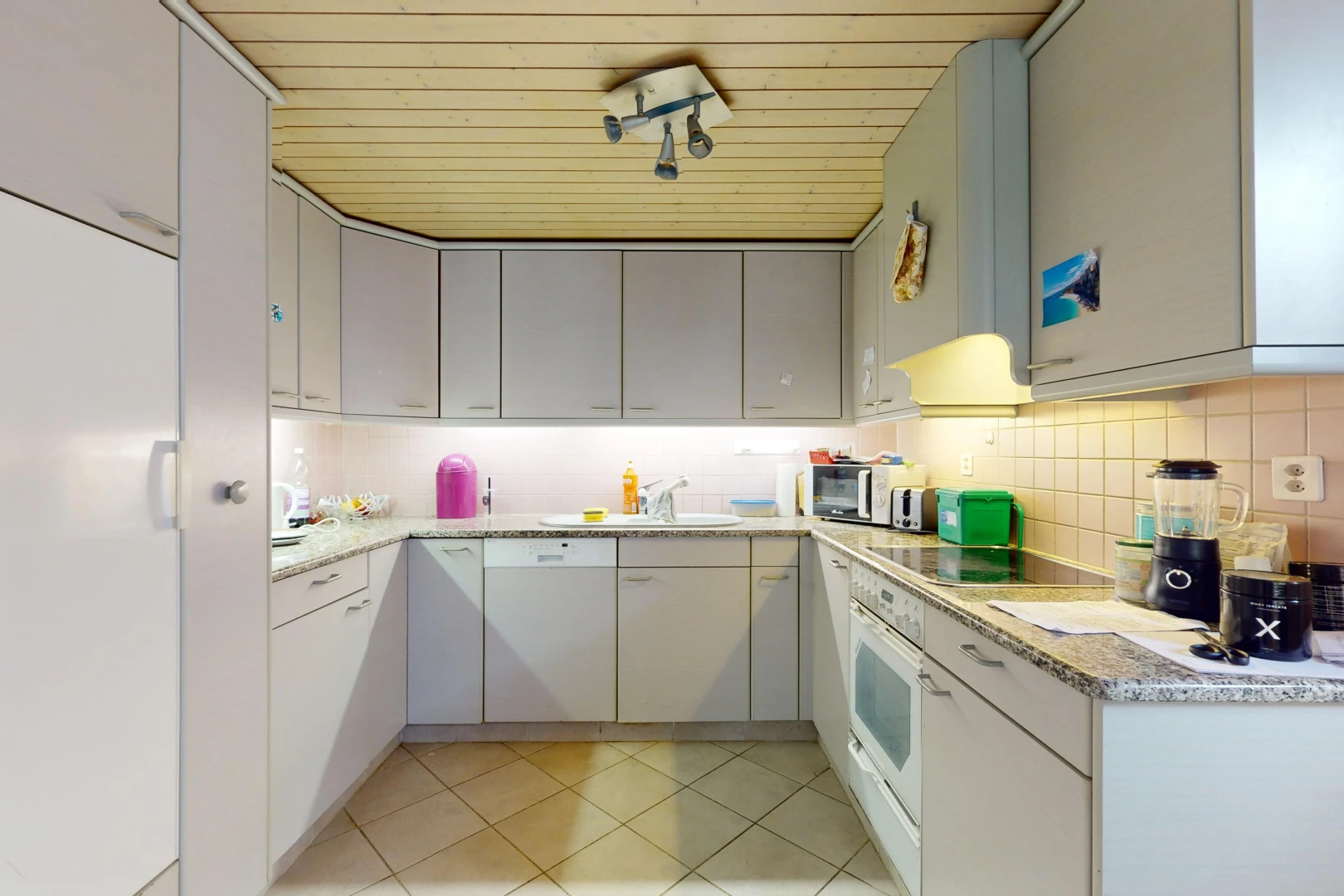 cuisine avec crédence, carrelage, meubles gris, et plan de travail en pierre