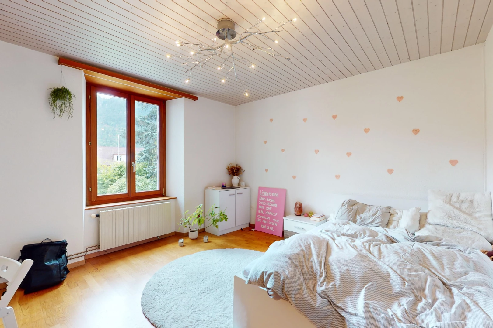 chambre avec plancher de bois, radiateur, et lumière naturelle