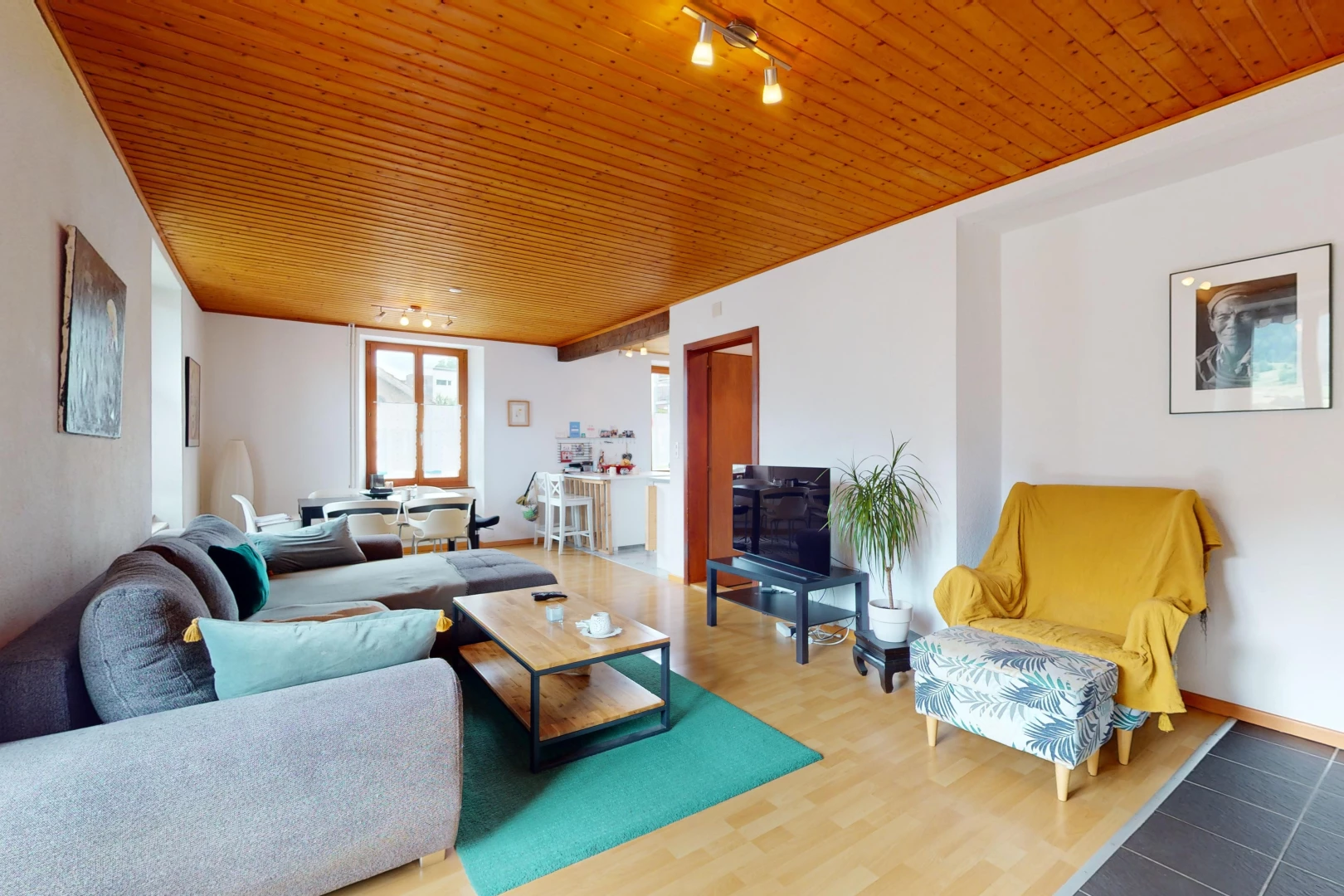 salon avec plafond de bois, plancher de bois, télévision, et éclairage sur rail