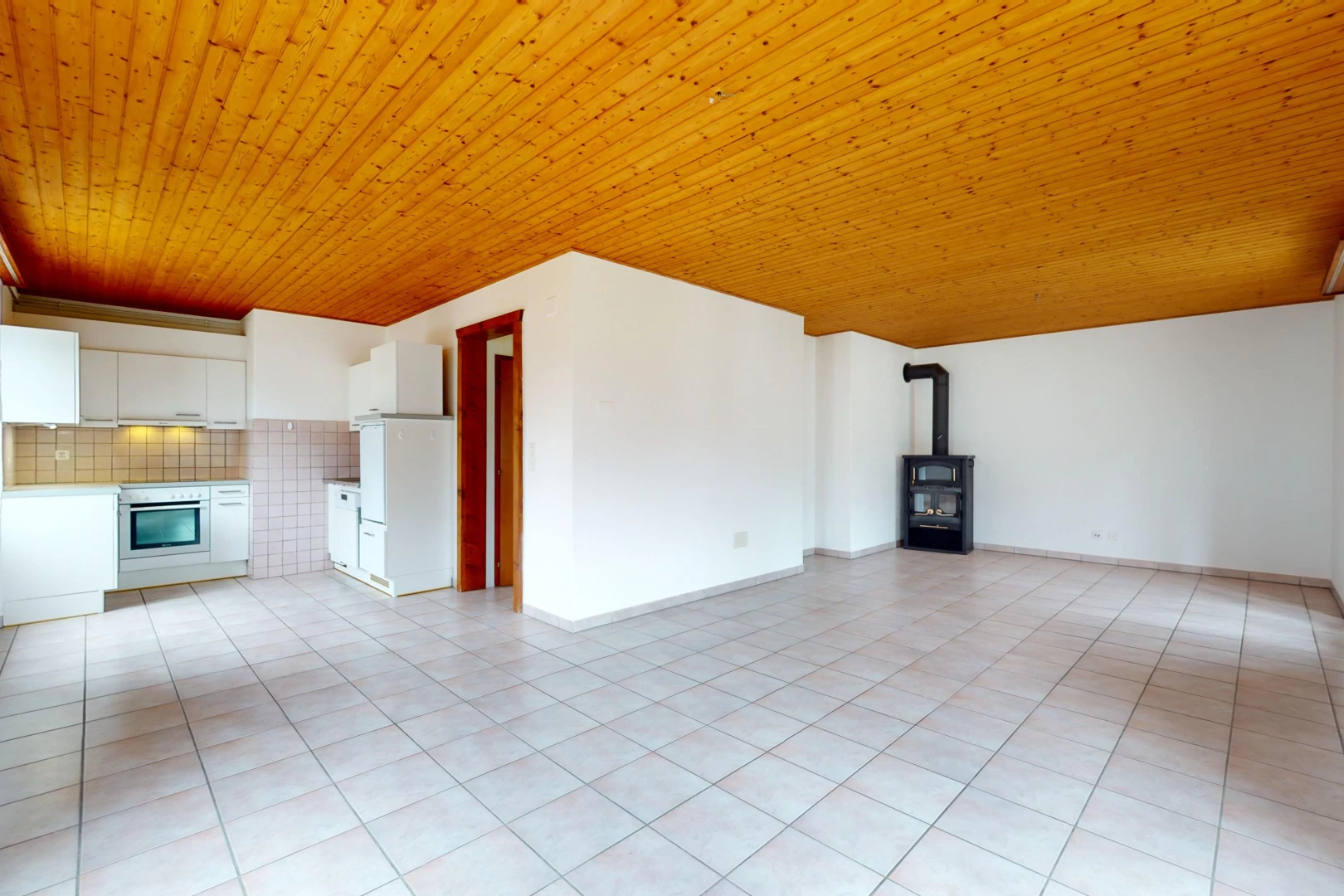 pièce vide avec plafond de bois, poêle à bois, et carrelage
