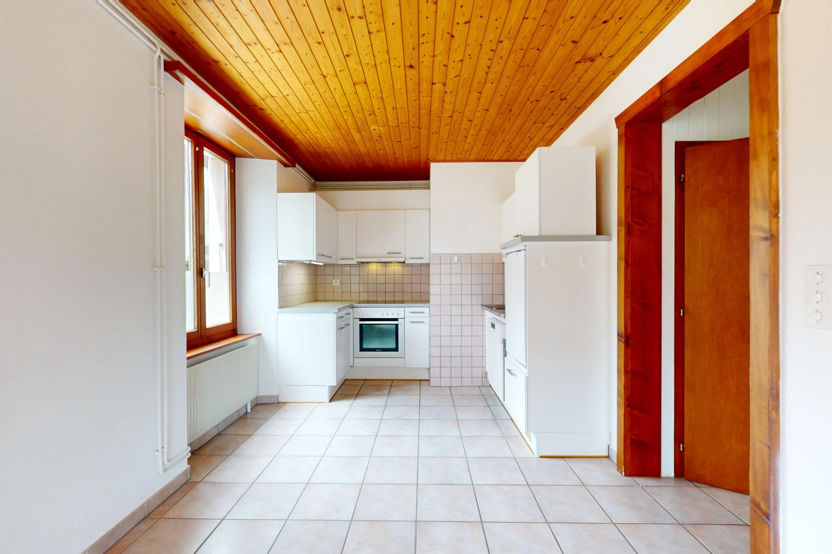cuisine avec plafond de bois, four, carrelage, meubles blancs, et crédence