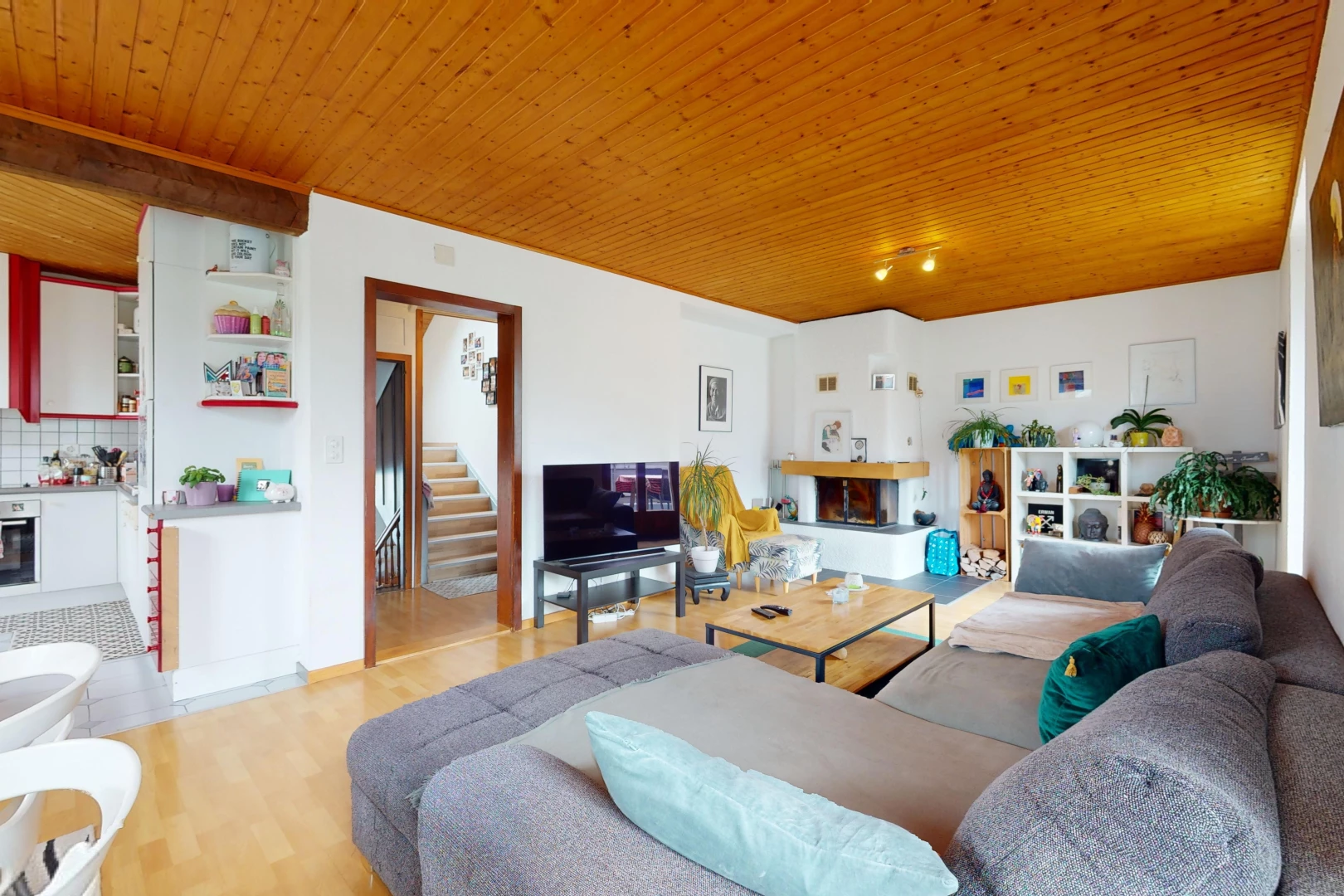 salon avec plafond de bois, cheminée, plancher de bois, et télévision