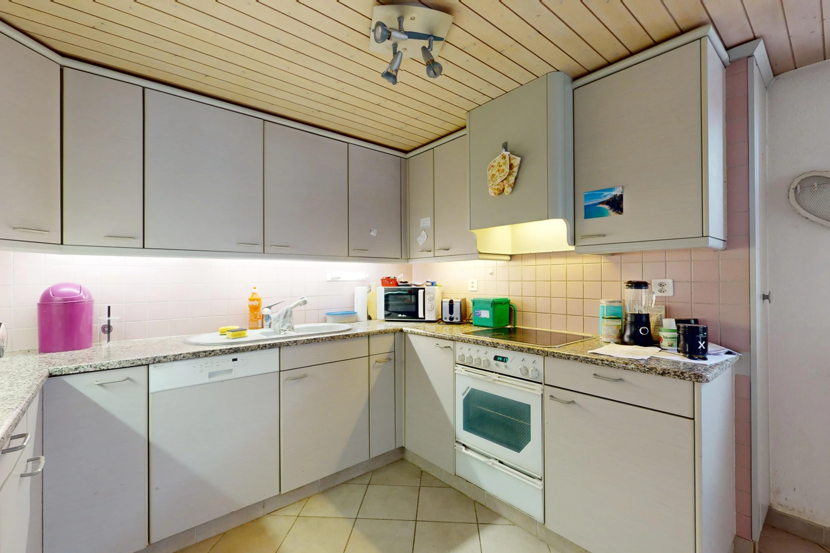 cuisine avec plafond de bois, carrelage, plan de travail en pierre, et four