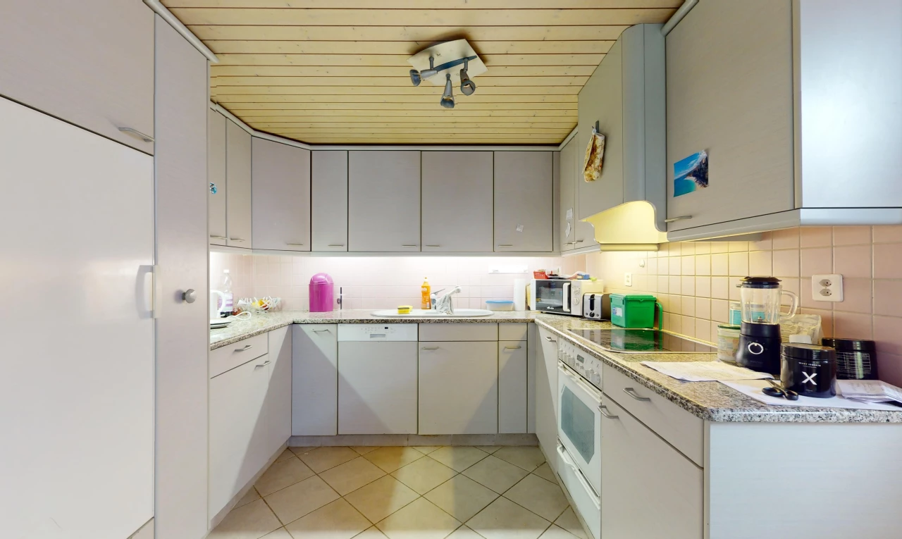 cuisine avec crédence, carrelage, meubles gris, et plan de travail en pierre
