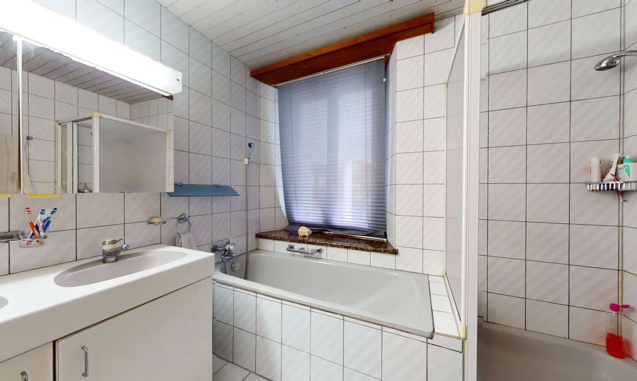 salle de bain avec baignoire, meuble-lavabo, vasque, miroir, et mur carrelé