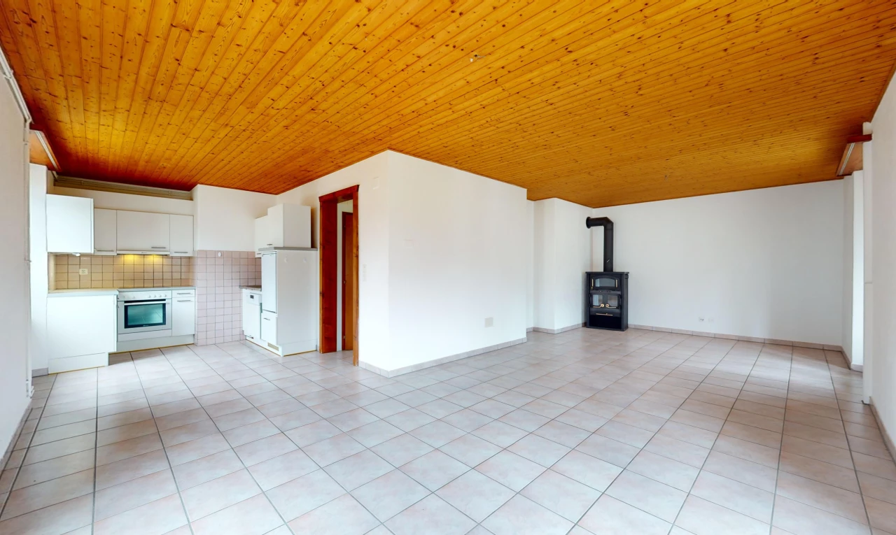 pièce vide avec plafond de bois, poêle à bois, et carrelage