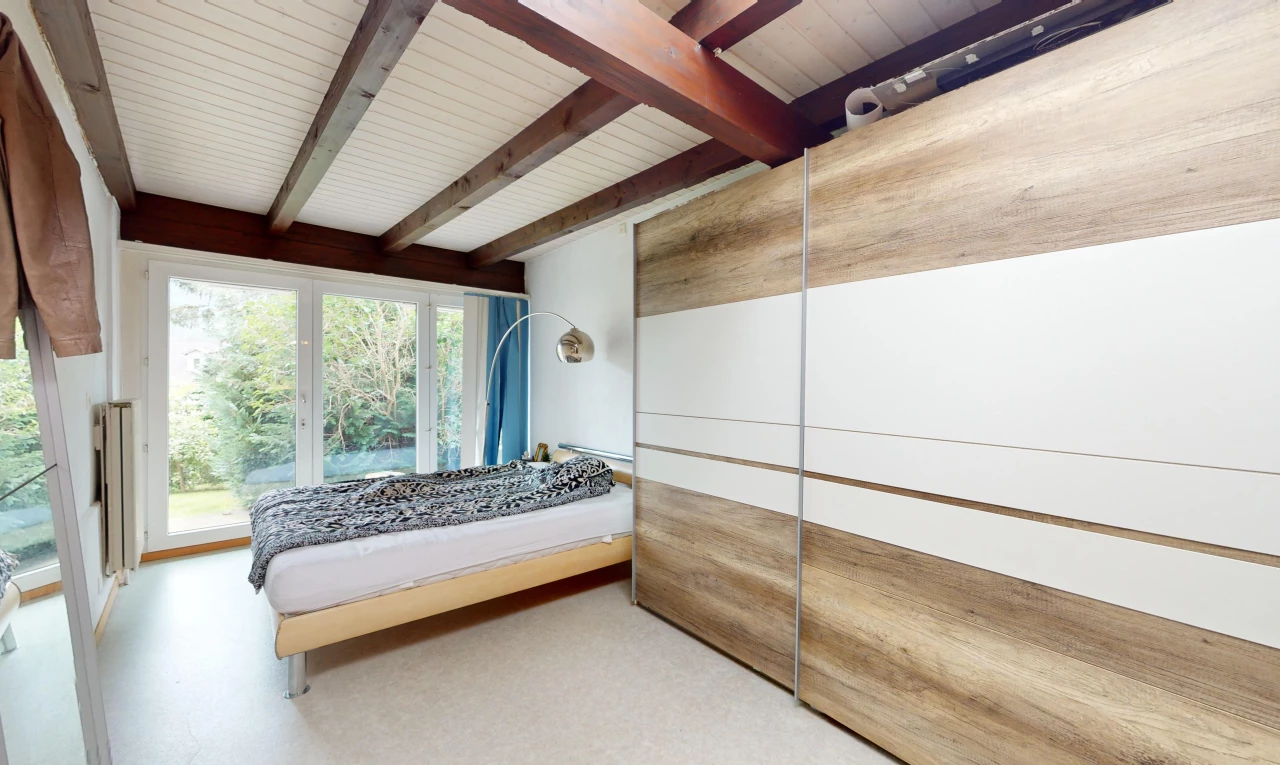 chambre avec lumière naturelle et poutres apparentes
