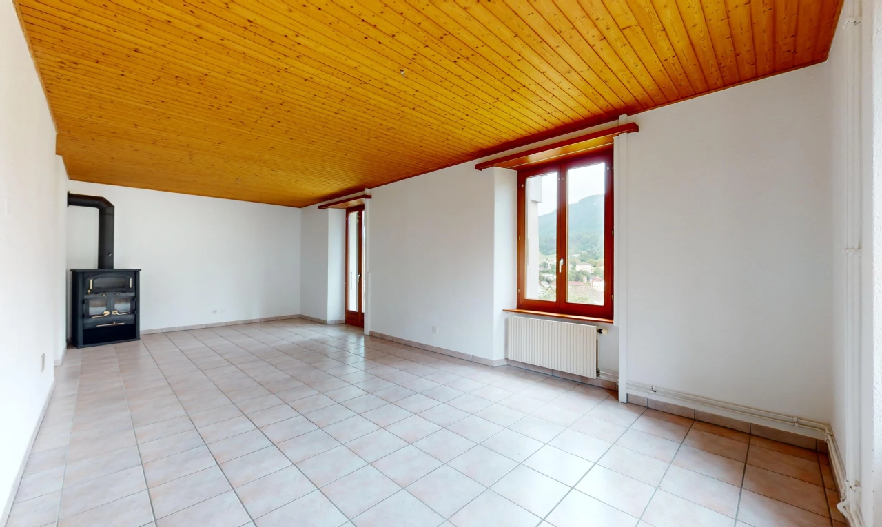 pièce vide avec plafond de bois, poêle à bois, carrelage, lumière naturelle, et radiateur