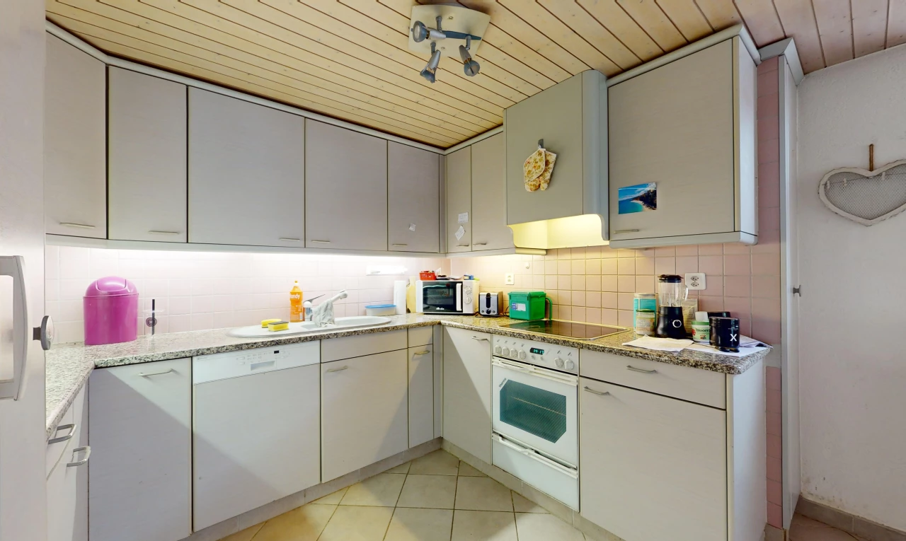 cuisine avec plafond de bois, carrelage, plan de travail en pierre, et four