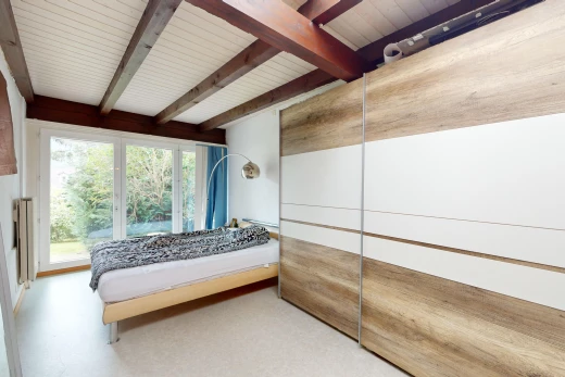chambre avec lumière naturelle et poutres apparentes