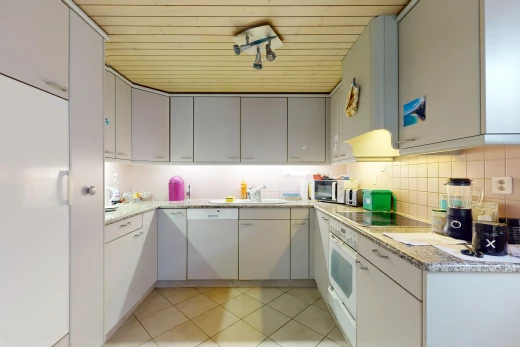 cuisine avec crédence, carrelage, meubles gris, et plan de travail en pierre