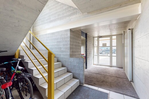 escaliers avec mur en béton, escaliers, plafond en béton, moquette, et lumière naturelle