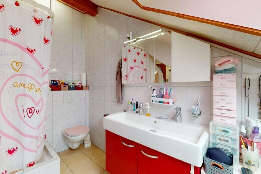 salle de bains avec salle de bain complète, lavabo (ou coiffeuse selon le contexte), mur en carrelage, toilette, et miroir