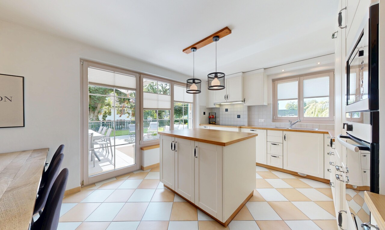 cuisine avec armoires blanches, dosseret, backsplash, plans de travail, et lumière naturelle