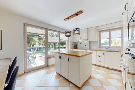 cuisine avec armoires blanches, dosseret, backsplash, plans de travail, et lumière naturelle