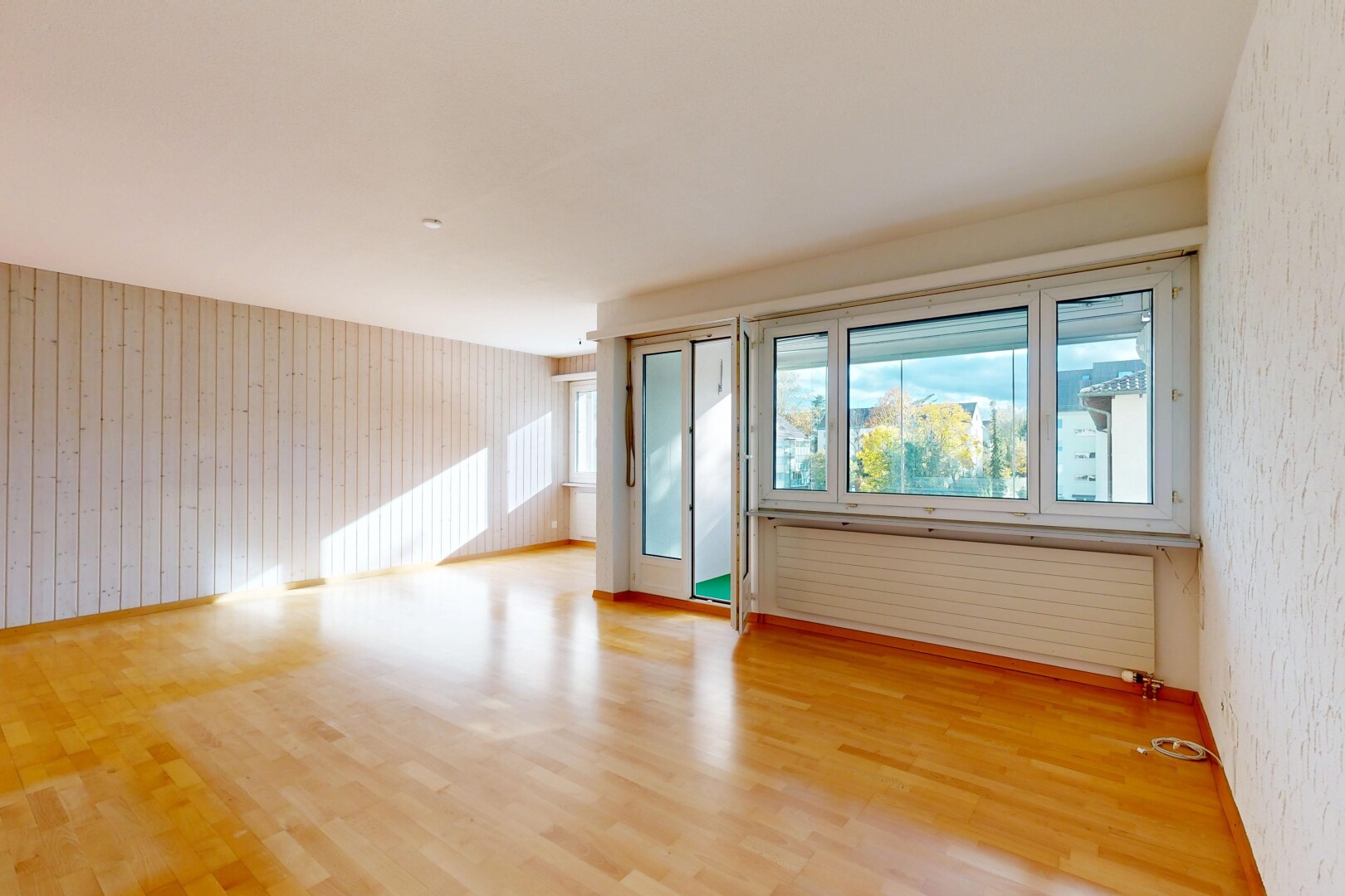 spare room featuring light wood-style floors, radiator heating unit, and wooden walls