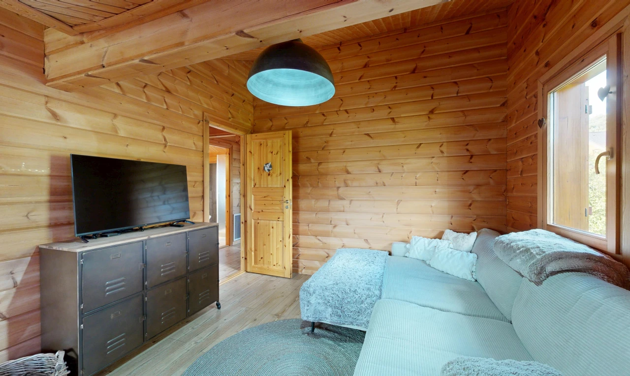 wohnzimmer mit fernseher, high end ceiling, natürliches licht, wood finish floor, und holzfußboden