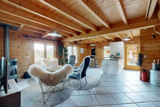 dining area featuring a wood stove, wooden walls, a wooden ceiling with exposed beams, and pendant lighting