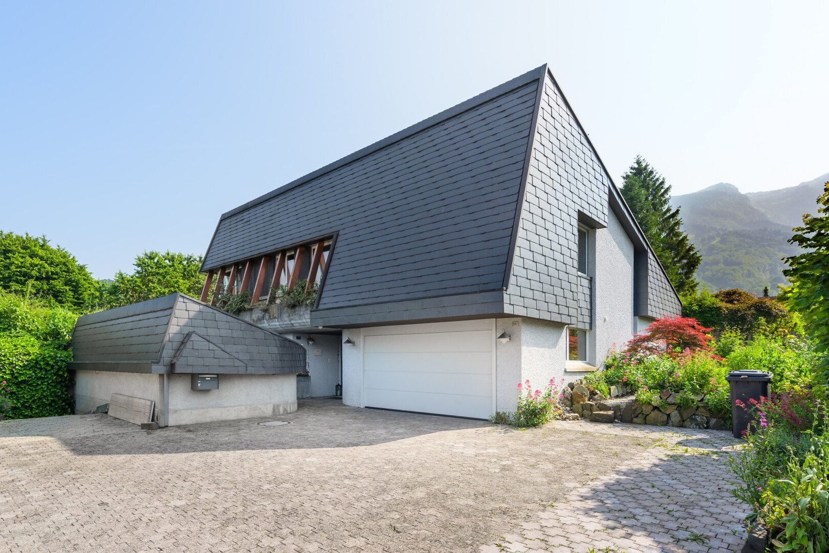 façade avec property visible, garage intégré, bardage en bardeaux, mountain view, et vue sur la montagne