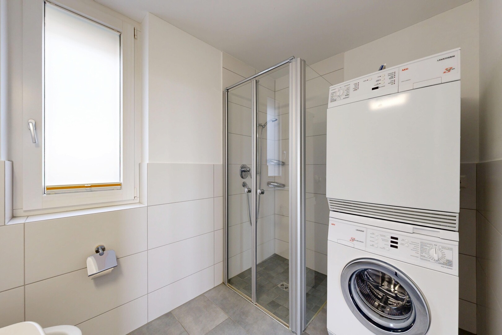 bathroom featuring a stall shower, tile walls, and stacked washer and clothes dryer