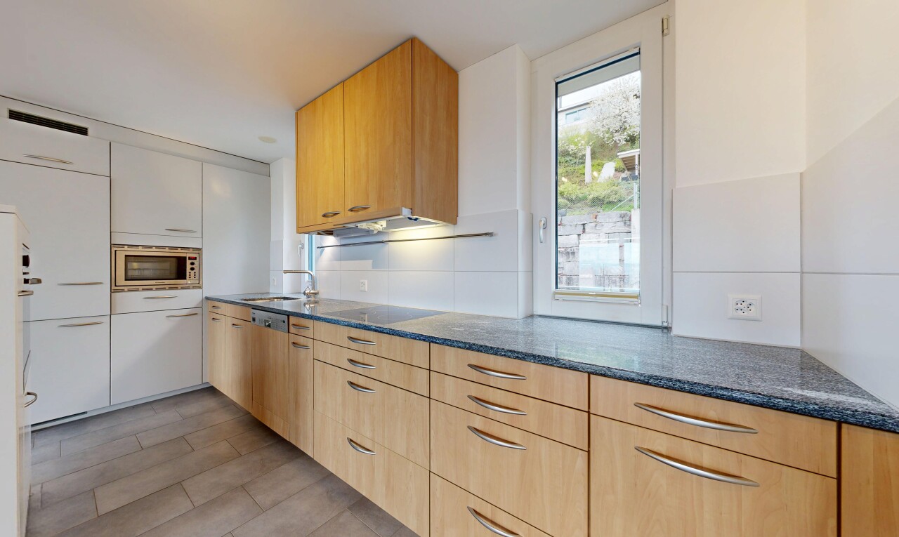 kitchen featuring dark stone counters, stainless steel microwave, light wood finish cabinets, dark wood-style floors, and black electric stovetop