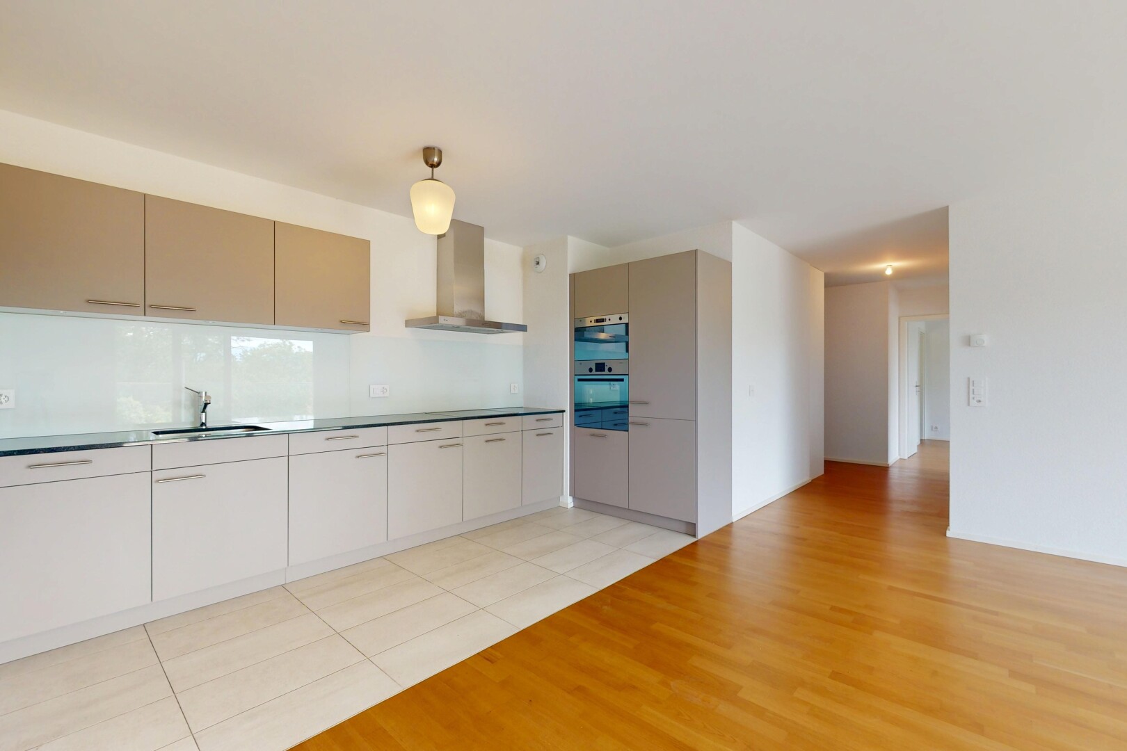 cuisine avec hotte, évier, cloison sèche, drywall, et sol en finition bois
