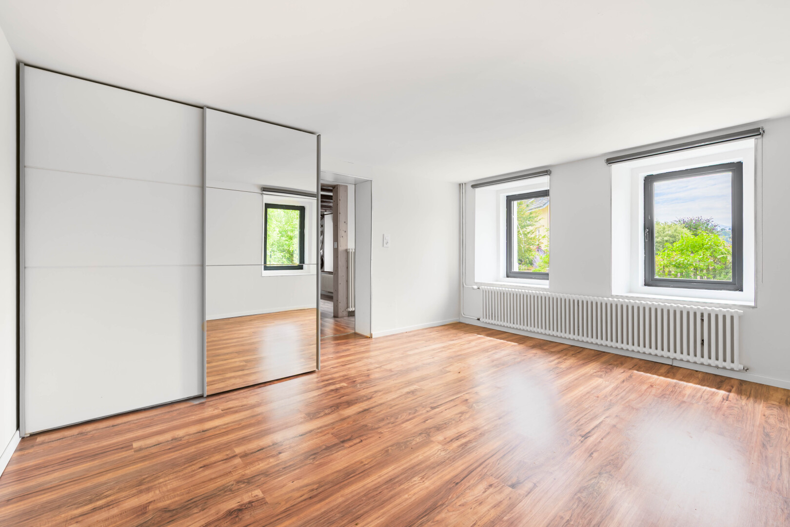 pièce vide avec radiateur, wood finish floor, sol en finition bois, natural light, et lumière naturelle
