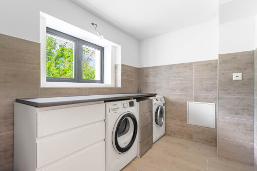 buanderie avec lave-linge et sèche-linge séparés, tile wall, mur en carrelage, inside property, et natural light