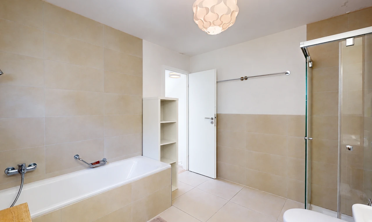 bathroom with a stall shower, tile walls, tiled tub, light tile patterned flooring, and wainscoting