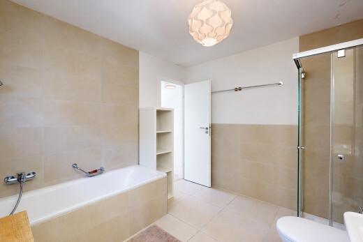 bathroom with a stall shower, tile walls, tiled tub, light tile patterned flooring, and wainscoting