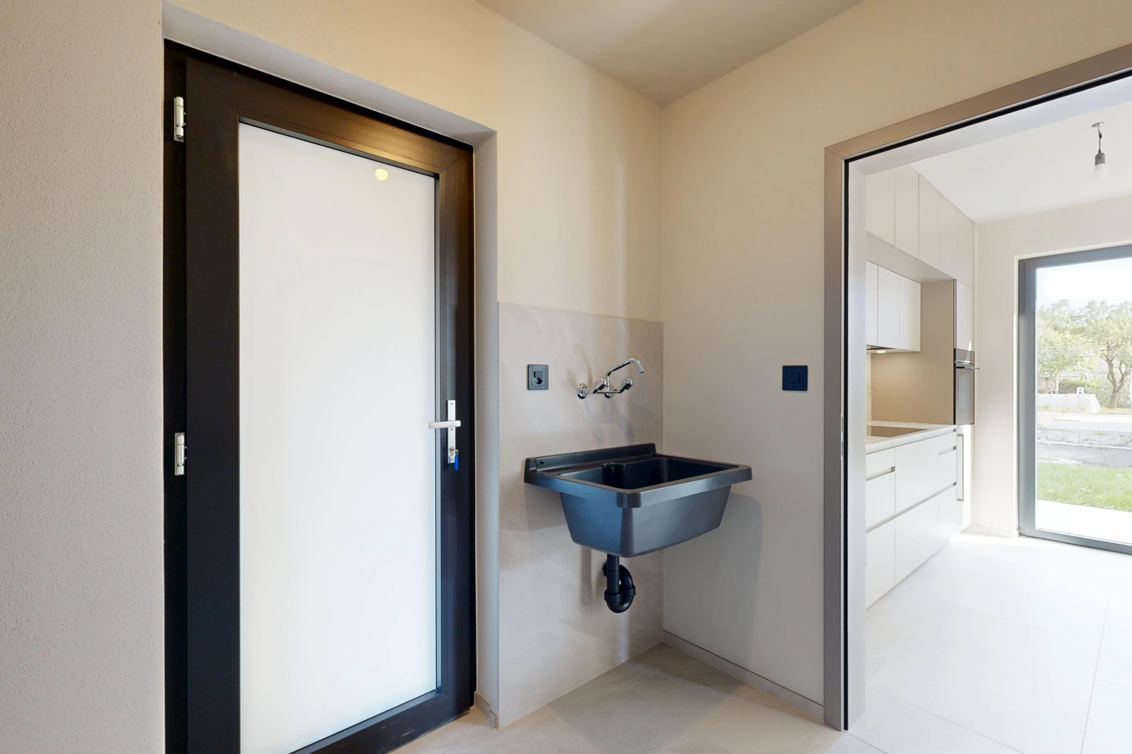 salle de bains avec accès à l'extérieur, light floor, évier, drywall, et cloison sèche