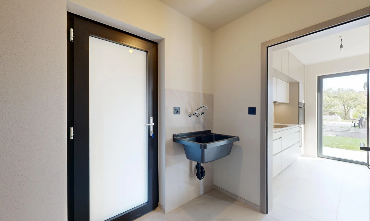 salle de bains avec accès à l'extérieur, light floor, évier, drywall, et cloison sèche