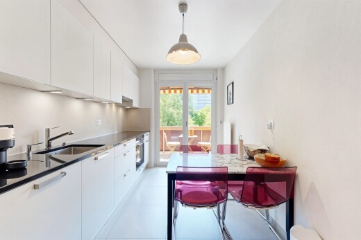 kitchen with white cabinets, hanging light fixtures, modern cabinets, light tile patterned floors, and dark stone counters