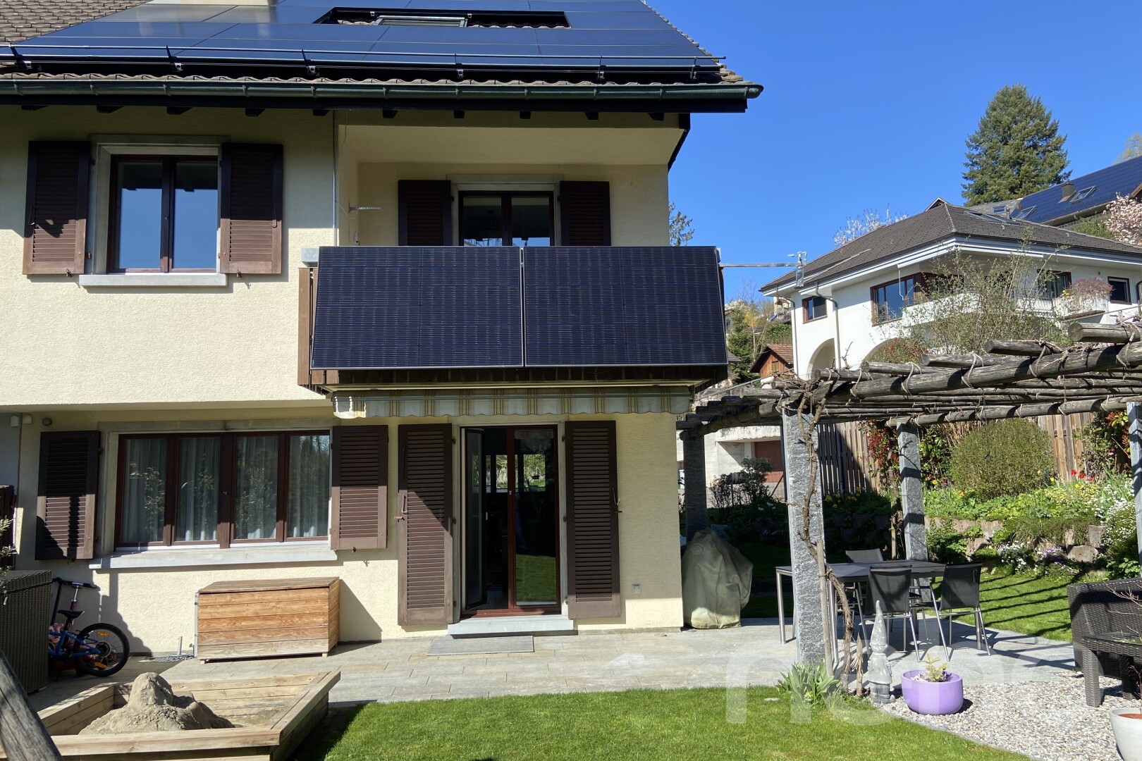 façade avec panneaux solaires, bardage en stuc, pergola, terrasse, et day time
