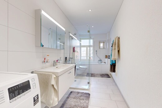 salle de bains avec lave-linge et sèche-linge, miroir, lavabo (ou coiffeuse selon le contexte), salle de bain complète, et douche