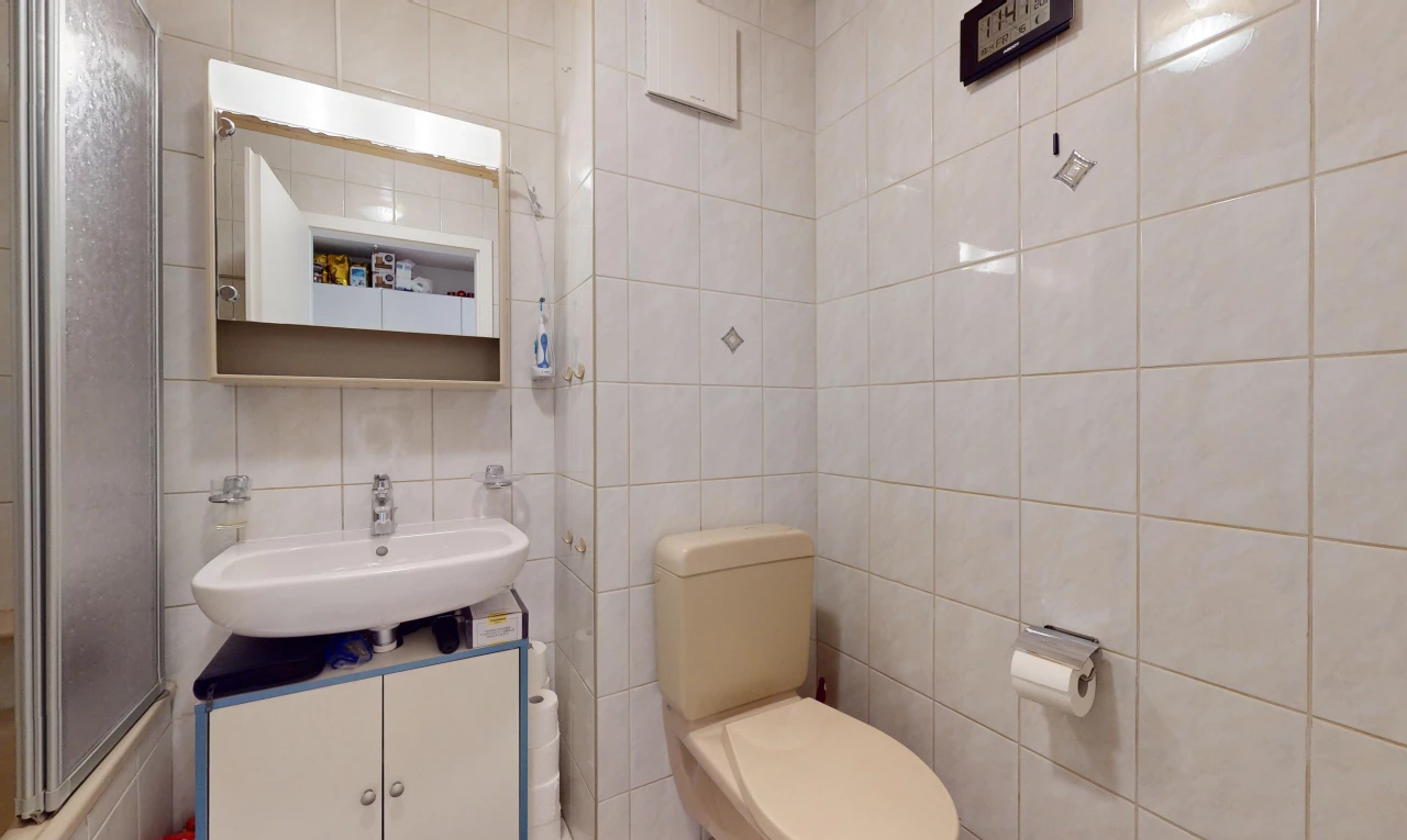 salle de bain avec mur carrelé, miroir, et vasque