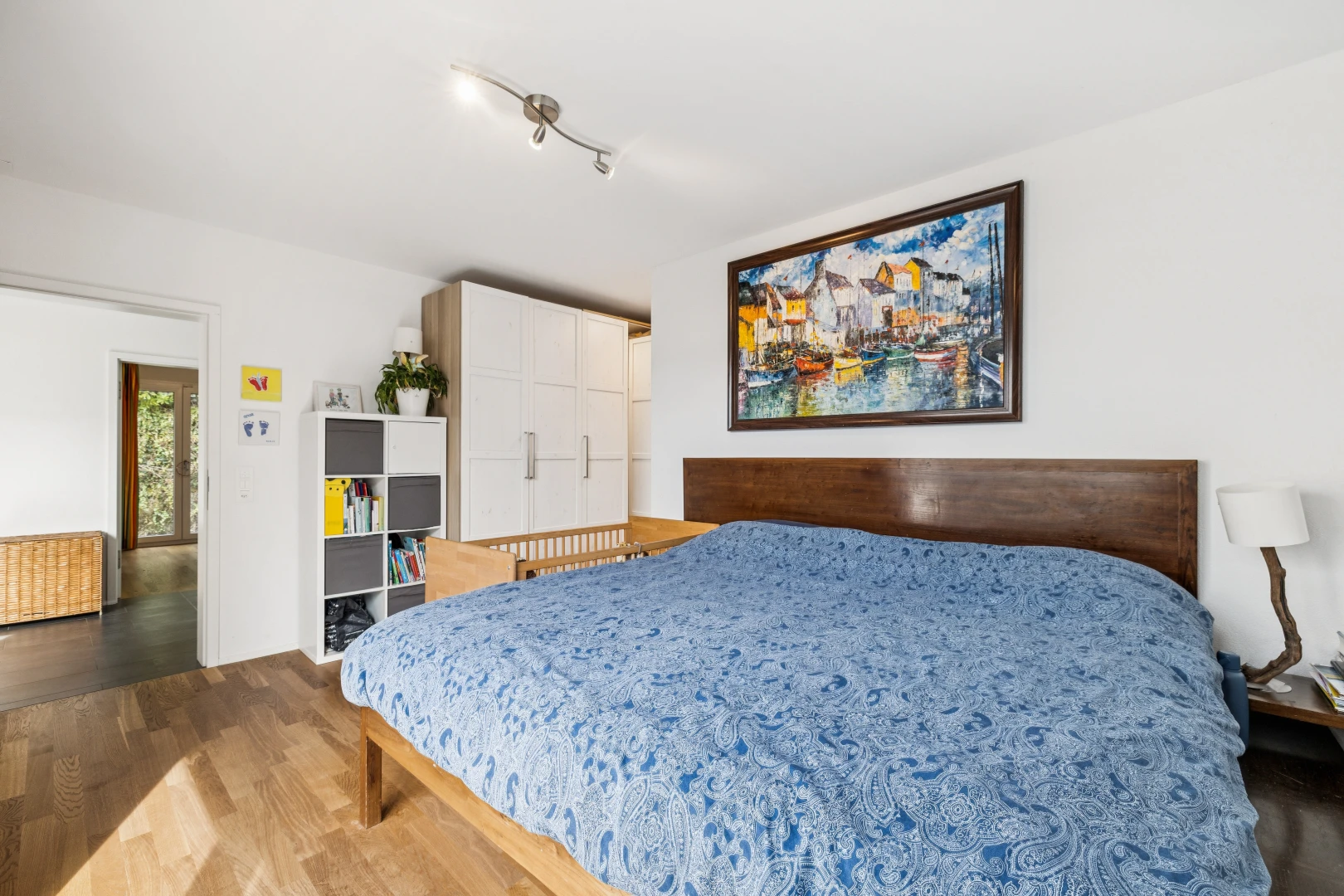 chambre avec éclairage sur rail, drywall, cloison sèche, wood finish floor, et sol en finition bois