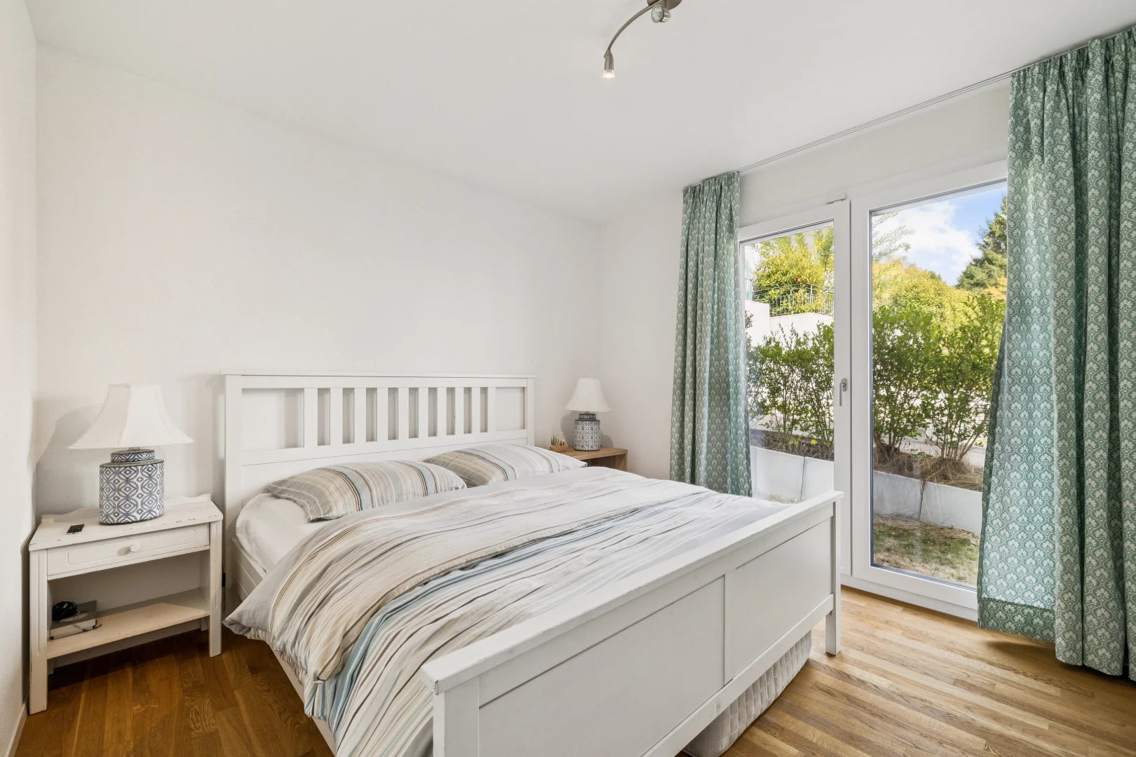 chambre avec éclairage sur rail, accès à l'extérieur, wood finish floor, sol en finition bois, et drywall