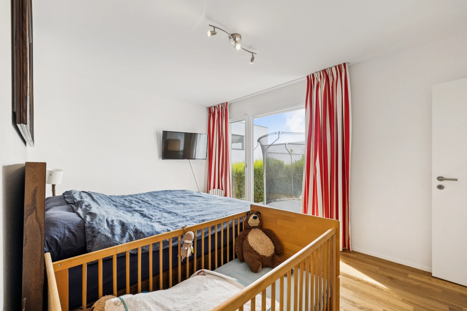 chambre avec éclairage sur rail, drywall, cloison sèche, télévision, et wood finish floor