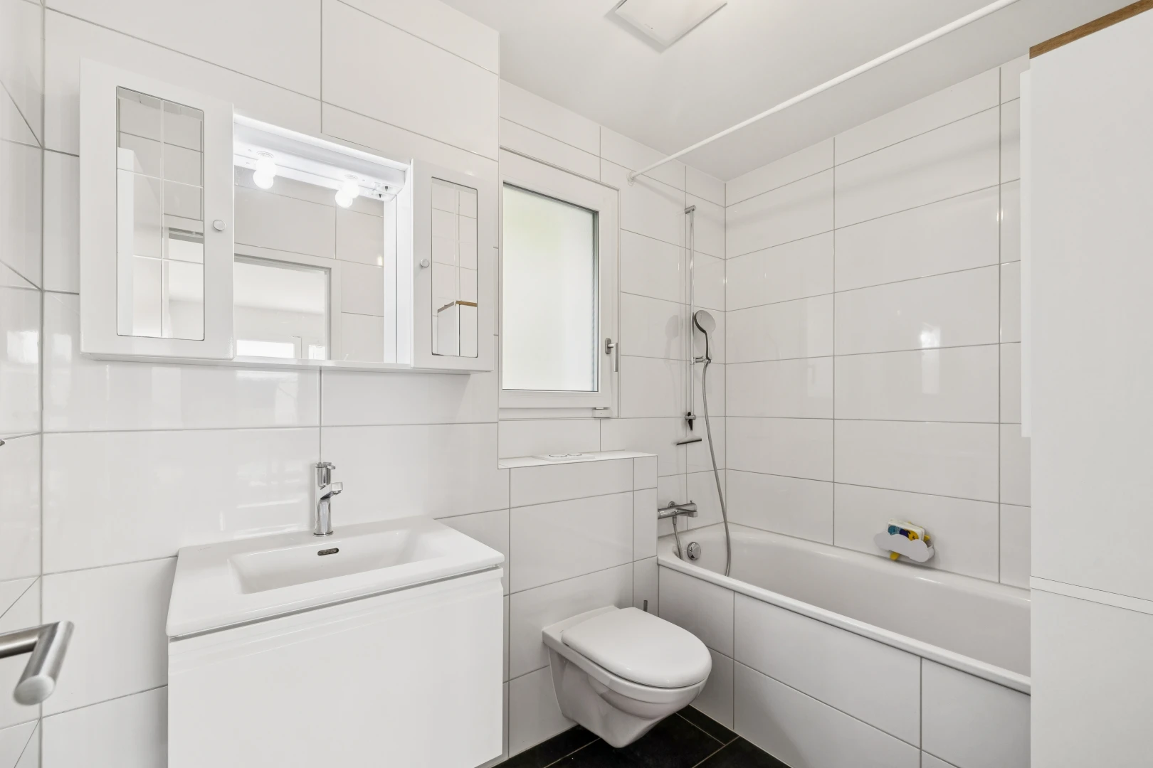 salle de bains avec douche-bain combinés, salle de bain complète, toilette, lavabo (ou coiffeuse selon le contexte), et tile wall