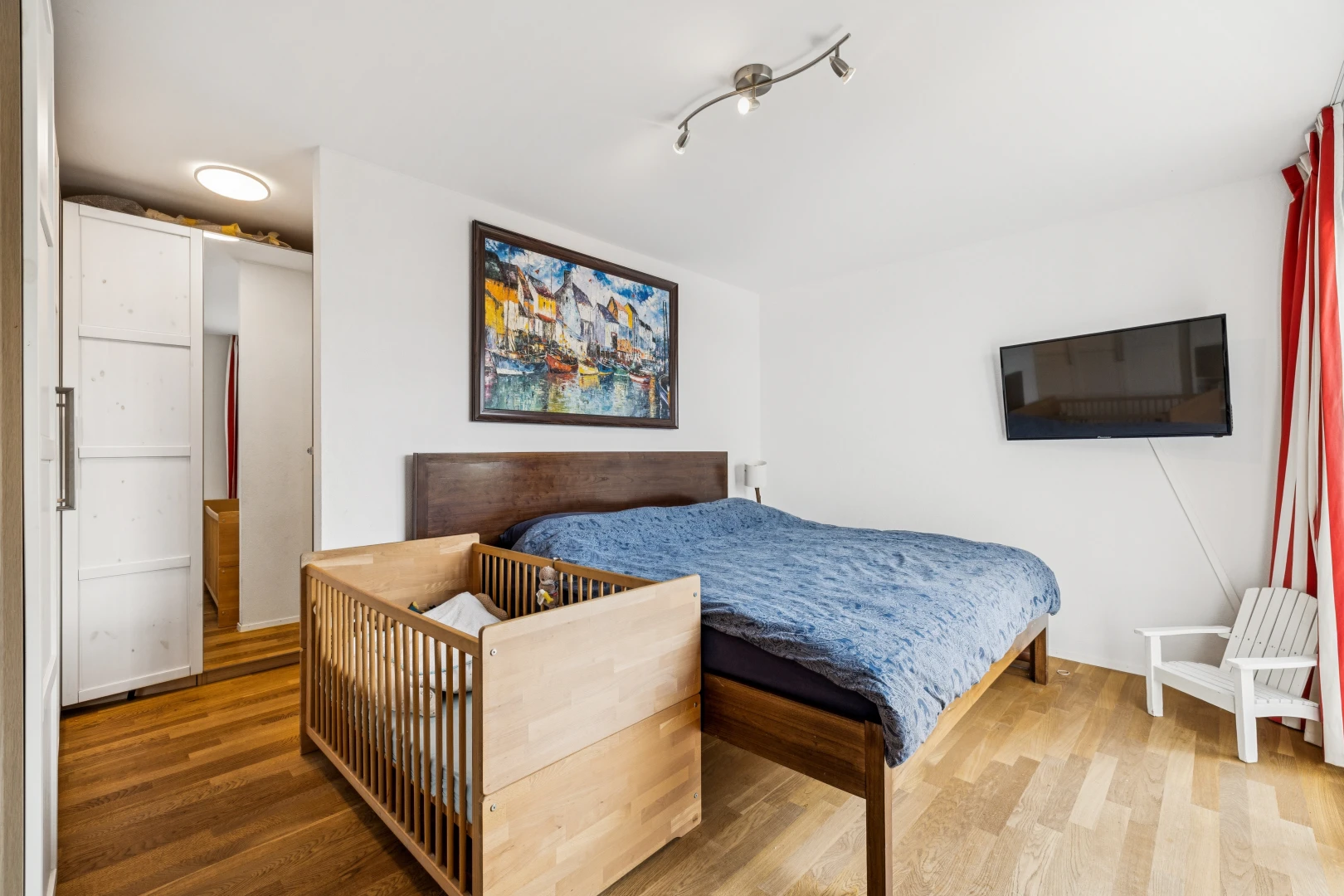 chambre avec télévision, drywall, cloison sèche, wood finish floor, et sol en finition bois