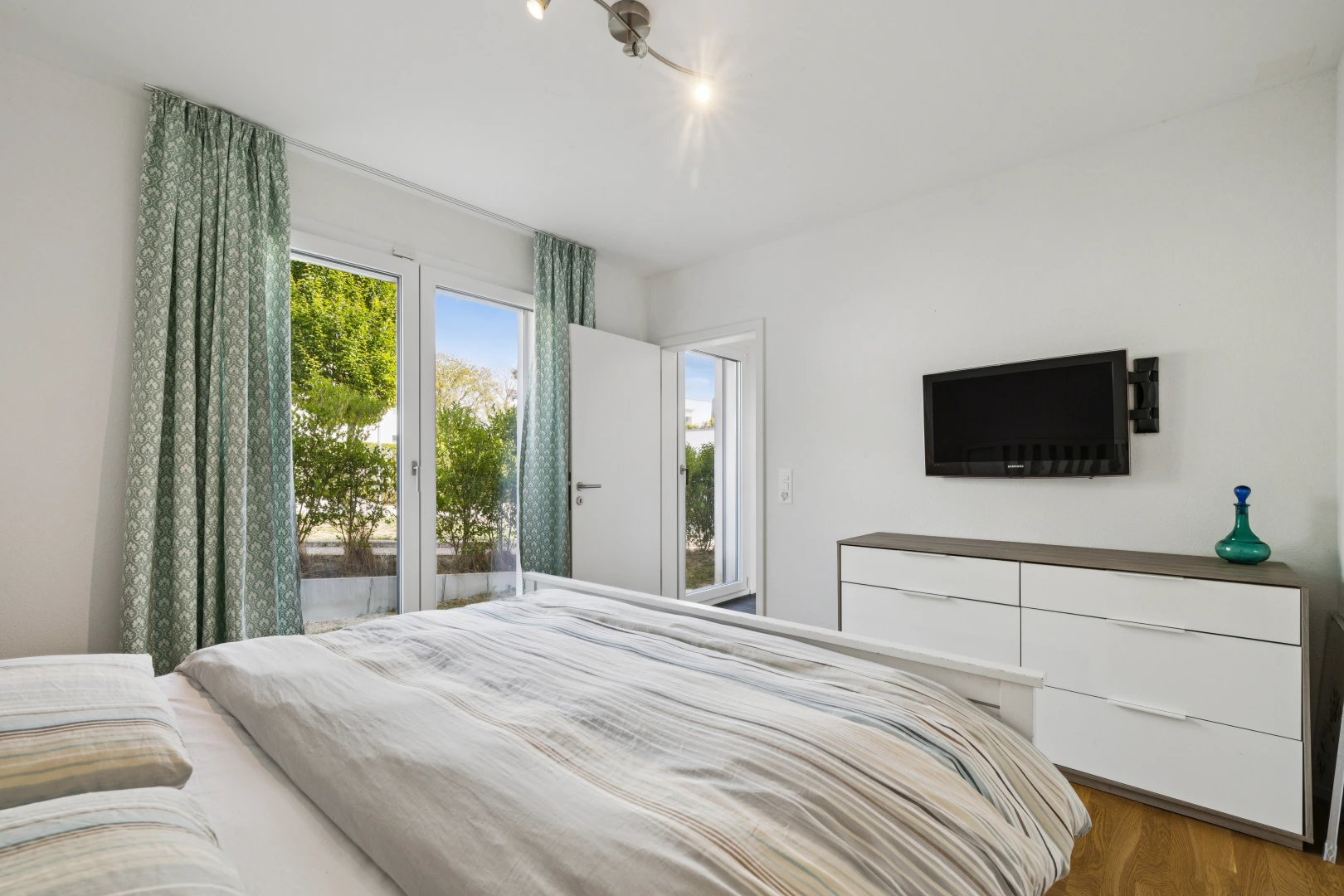 chambre avec télévision, accès à l'extérieur, drywall, cloison sèche, et wood finish floor