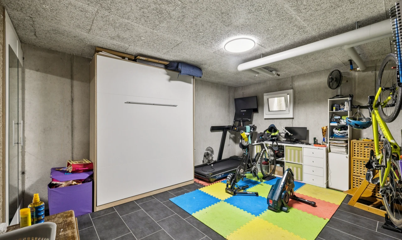 gym avec sous-sol, concrete wall, mur en béton, dark floor, et télévision
