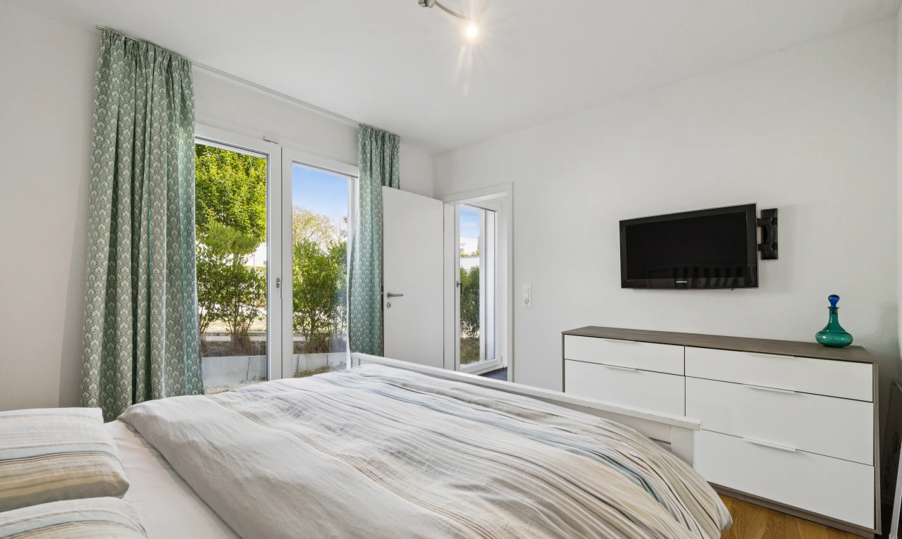 chambre avec télévision, accès à l'extérieur, drywall, cloison sèche, et wood finish floor