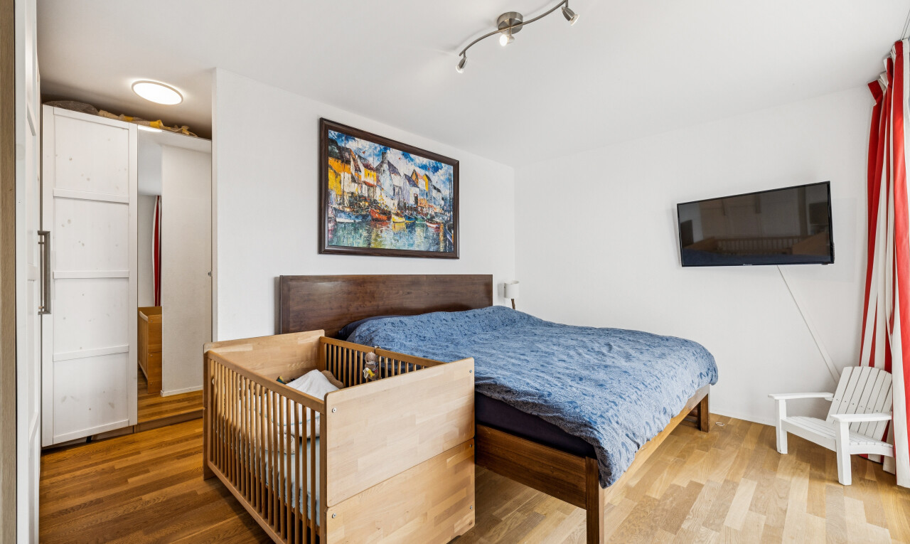 zimmer / schlafzimmer mit fernseher, drywall, gipskartonwand, wood finish floor, und holzfußboden