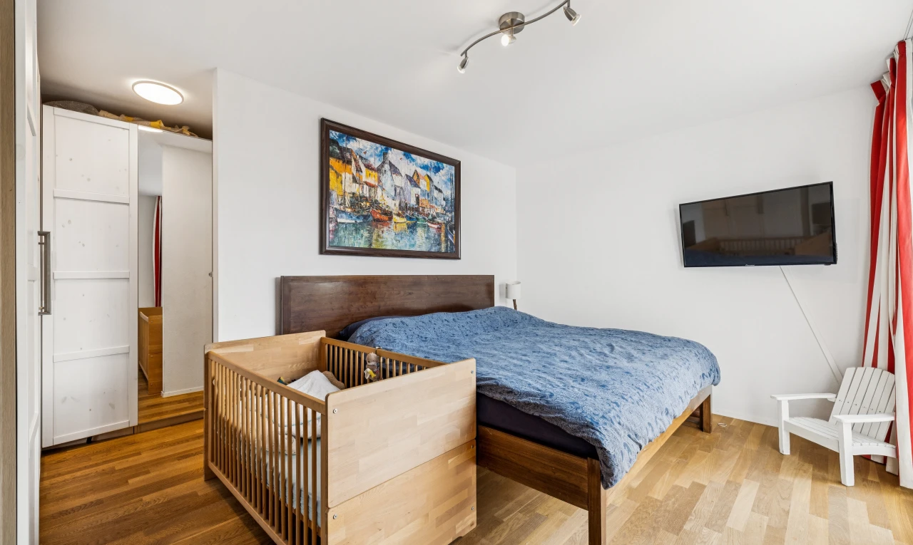 chambre avec télévision, drywall, cloison sèche, wood finish floor, et sol en finition bois