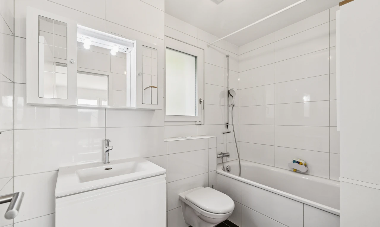 salle de bains avec douche-bain combinés, salle de bain complète, toilette, lavabo (ou coiffeuse selon le contexte), et tile wall